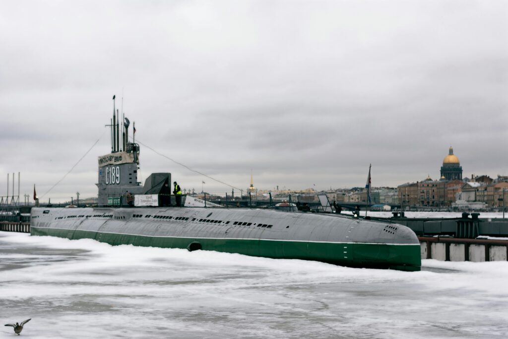 Submarine surrounded by ice in Saint Petersburg with historic cityscape in background.