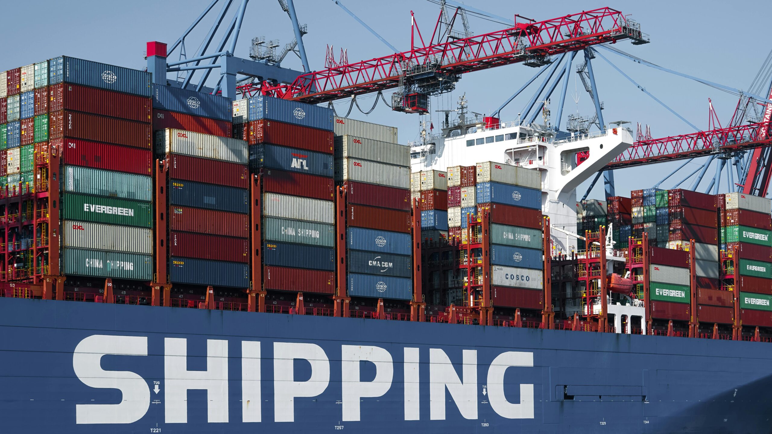 A container ship in Hamburg port with cranes, showcasing global commerce and transport.
